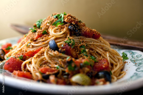 Close up of pasta with tomatoes, capers, olives and breadcrumbs photo