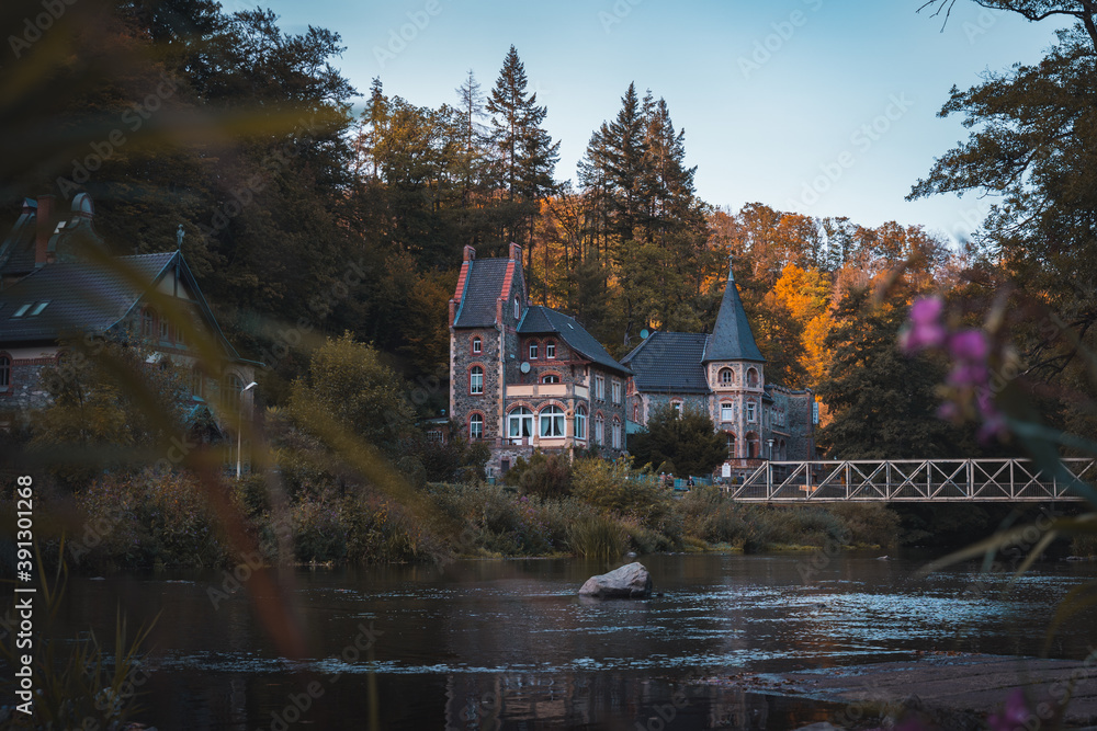 Traditionelle deutsches Haus am Ufer eines Flusses, während des Herbst im Harz (Querformat)