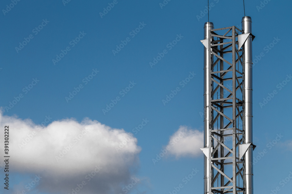 Shiny metal chimney with lightning rods against the background of a blue sky with clouds. Shiny metal chimney with lightning rods against the background of a blue sky with clouds.