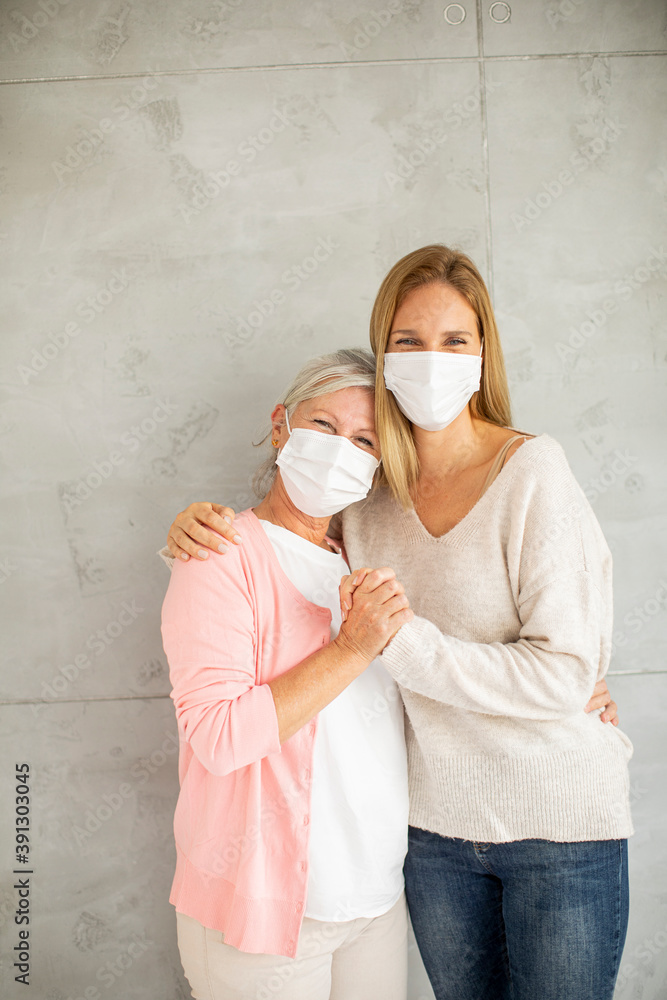 Φωτογραφία Senior woman with caring daughter at home wearing medical masks