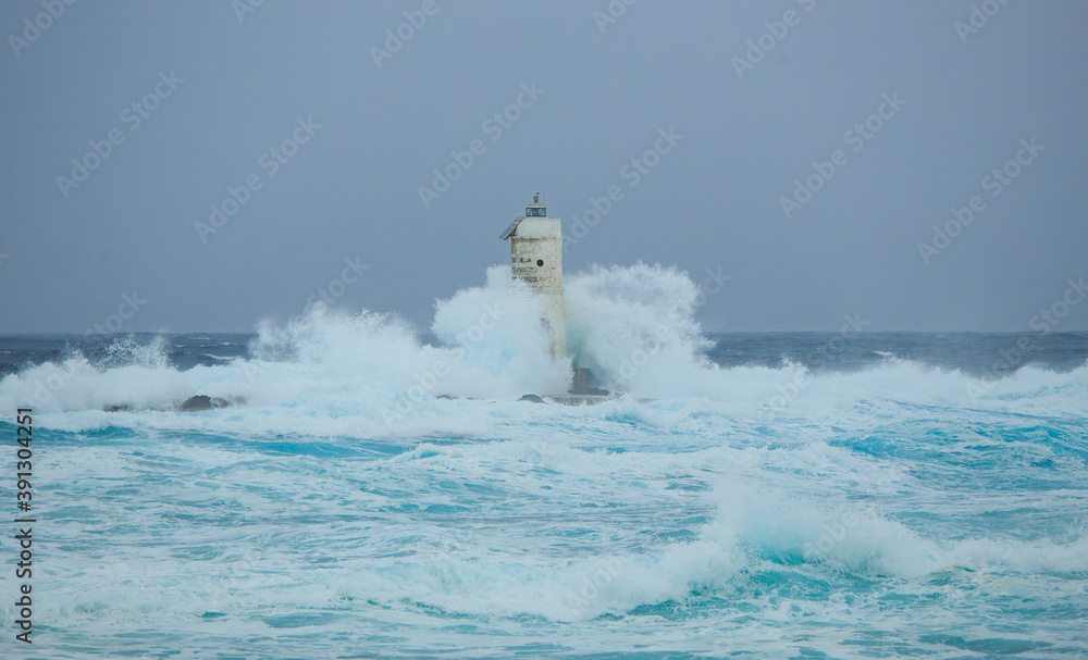 The lighthouse of the Mangiabarche shrouded by the waves of a mistral wind storm
