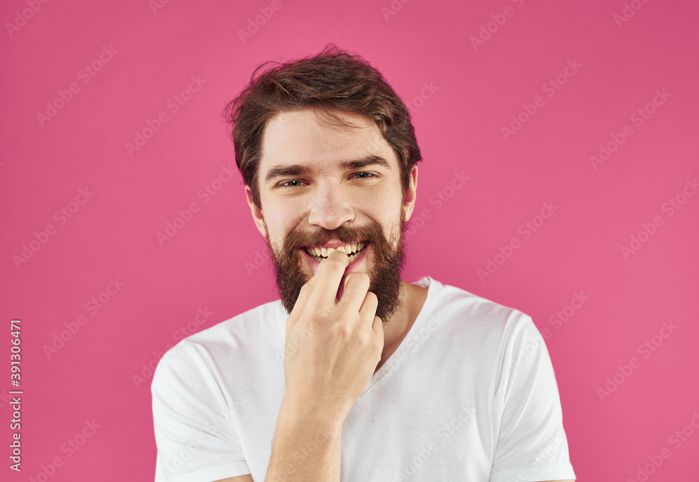 Portrait of a happy guy in a white T-shirt with a thick beard on a pink background Portrait of a happy guy in a white T-shirt with a thick beard on a pink background