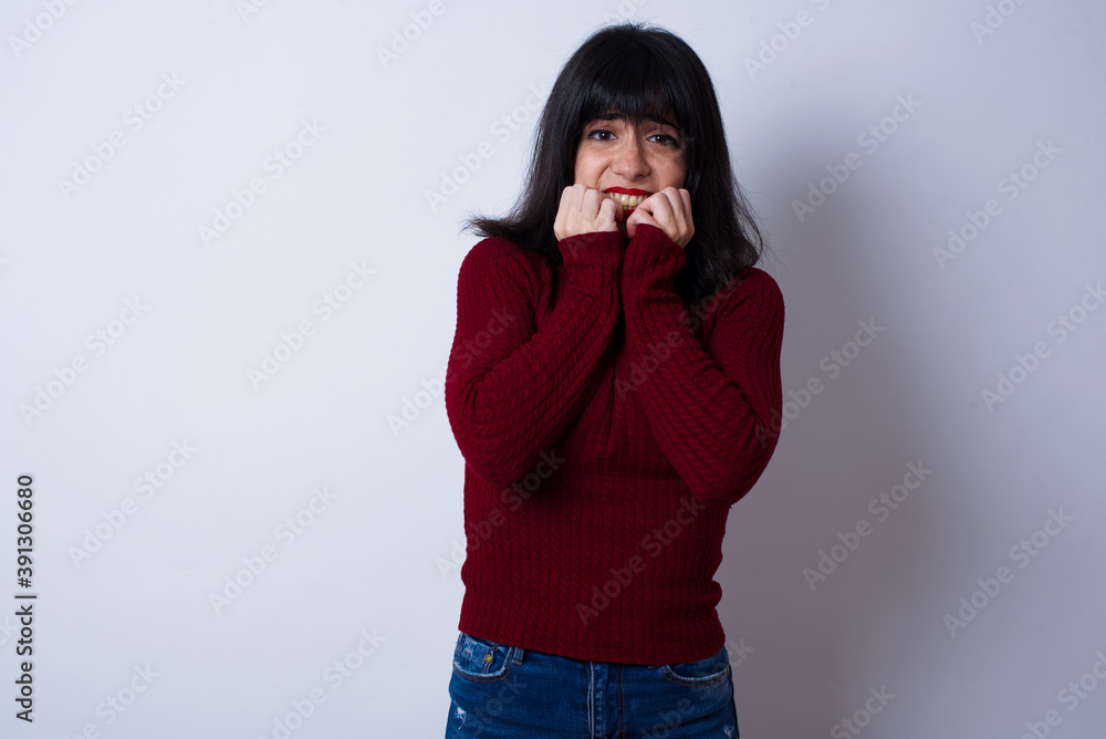 Anxiety - Beautiful young Caucasian woman standing against white background covering his mouth with hands scared from something or someone bitting nails. Anxiety - Beautiful young Caucasian woman standing against white background covering his mouth with hands scared from something or someone bitting nails.