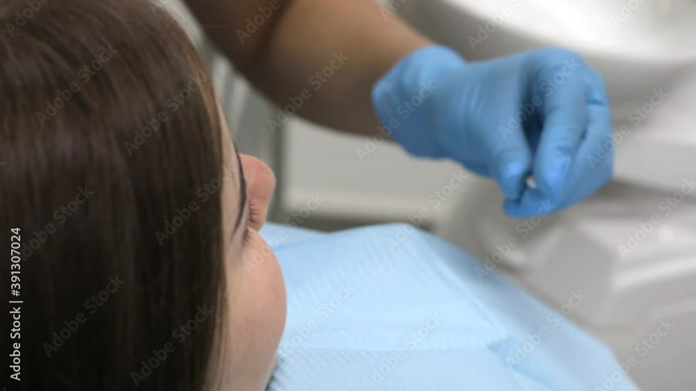 The patient examines the veneer model in the hands of the dentist The patient examines the veneer model in the hands of the dentist