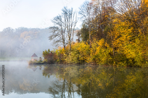 Beautiful landscape with lake and forest. Amazing nature wallpaper. Autumn trees in foggy morning. Romantic place. 