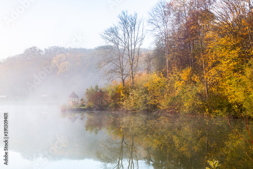 Beautiful landscape with lake and forest. Amazing nature wallpaper. Autumn trees in foggy morning. Romantic place. 