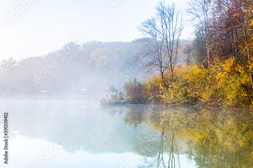 Beautiful landscape with lake and forest. Amazing nature wallpaper. Autumn trees in foggy morning. Romantic place.  © romeof