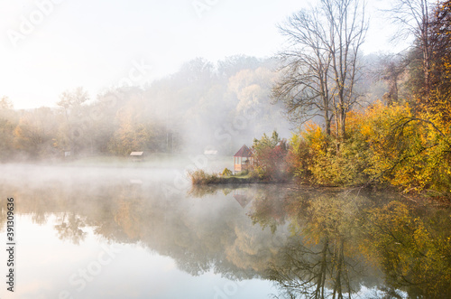 Beautiful landscape with lake and forest. Amazing nature wallpaper. Autumn trees in foggy morning. Romantic place. 