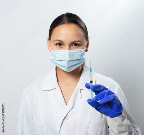 Woman doctor in a protective mask with a syringe in hand.
