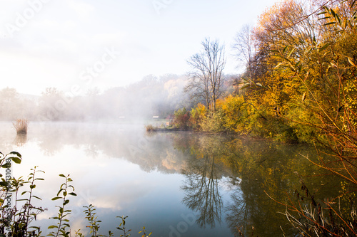 Beautiful landscape with lake and forest. Amazing nature wallpaper. Autumn trees in foggy morning. Romantic place. 