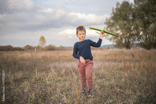 Happy child playing outdoors. Boy play airplane. Little kid dreams of being a pilot.