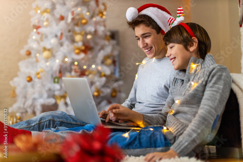 Two Boys Using Laptop by Christmas Tree
