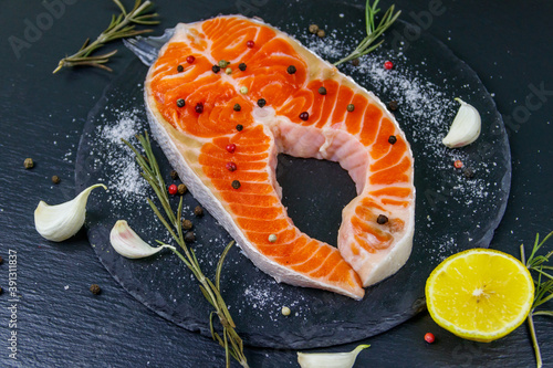 Raw salmon steak with spices on black slate