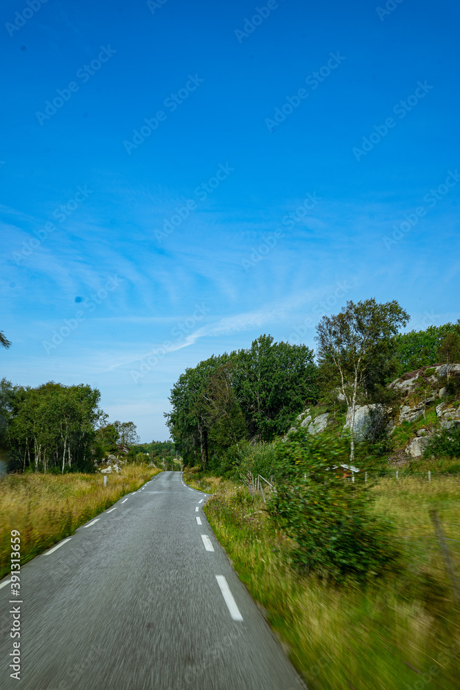 Fototapeta premium Street next to trees with hills all around it