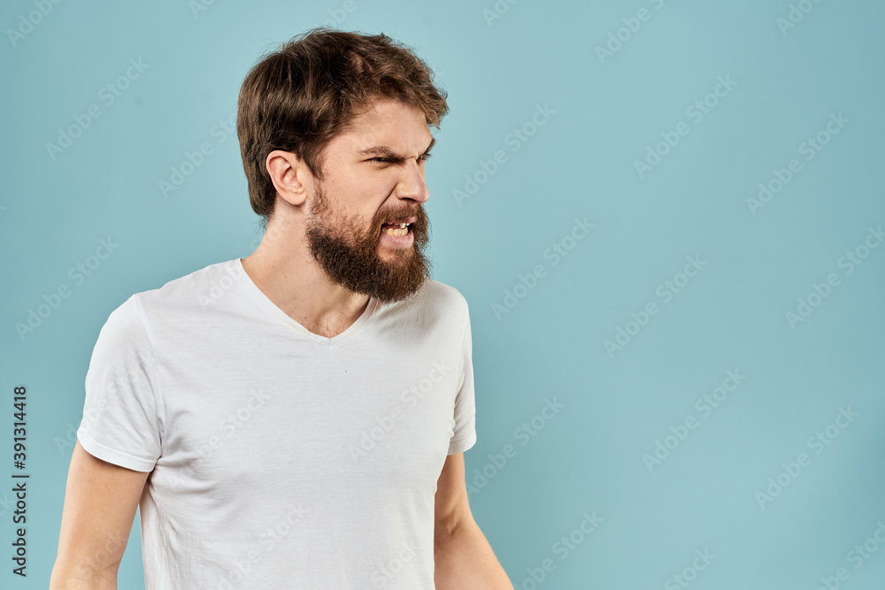 Man gestures with his hands emotions displeasure white t-shirt blue background Man gestures with his hands emotions displeasure white t-shirt blue background