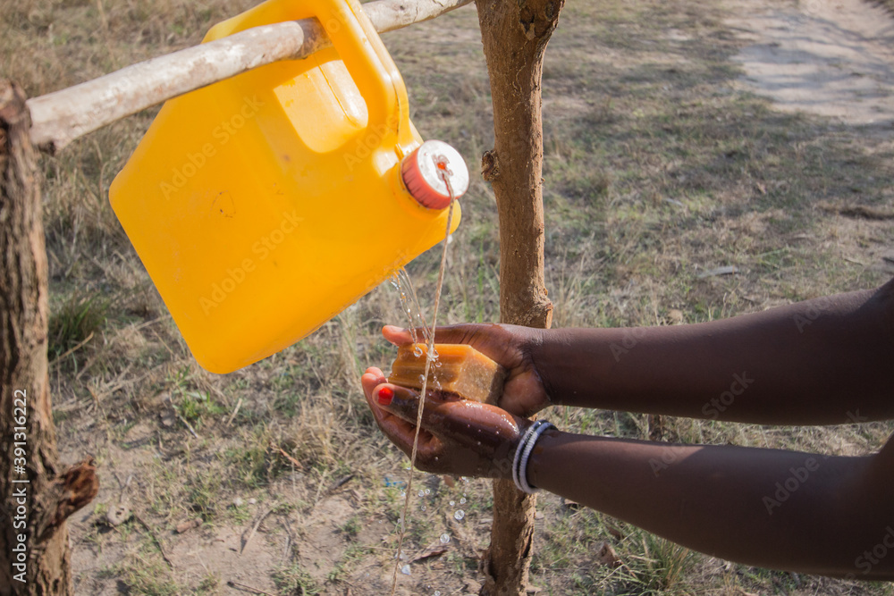 Hand washing using african soap bar. And the innovation tool called tippy tap made of 5 liter can of water and a string, supported by two tree logs Hand washing using african soap bar. And the innovation tool called tippy tap made of 5 liter can of water and a string, supported by two tree logs
