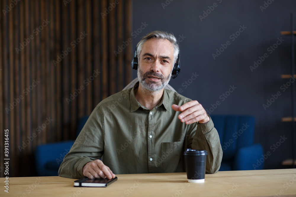 Portrait of grey-haired senior handsome man teaching online. Online education, remote working, home education. Online meeting, video call, video conference, courses online. Portrait of grey-haired senior handsome man teaching online. Online education, remote working, home education. Online meeting, video call, video conference, courses online.
