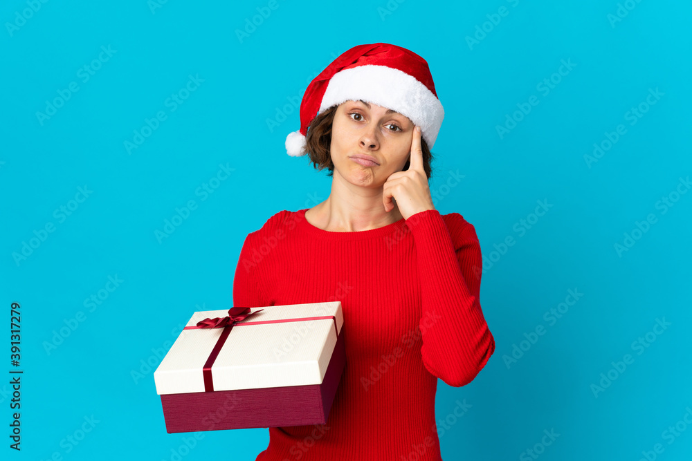 English girl with christmas hat holding a present isolated on blue background thinking an idea English girl with christmas hat holding a present isolated on blue background thinking an idea
