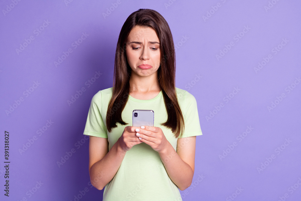 Photo portrait of sad upset girl typing texting message on mobile phone crying isolated on bright purple color background Photo portrait of sad upset girl typing texting message on mobile phone crying isolated on bright purple color background
