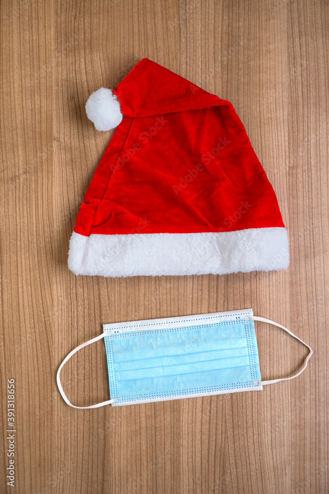 Santa Claus hat and face mask creative minimal concept flat lay of corona Christmas during coronavirus covid-19 pandemic Santa Claus hat and face mask creative minimal concept flat lay of corona Christmas during coronavirus covid-19 pandemic