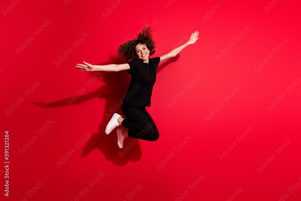 Photo portrait full body view of woman spreading hands like plane jumping up isolated on vivid red colored background