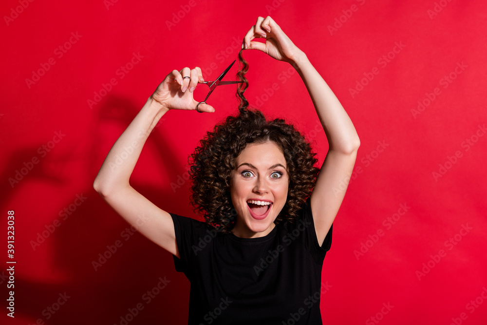Portrait of wavy attractive girl cut hair hold scissors wear black t-shirt isolated on red color background Portrait of wavy attractive girl cut hair hold scissors wear black t-shirt isolated on red color background