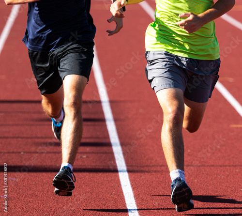 Two runners running on a red track