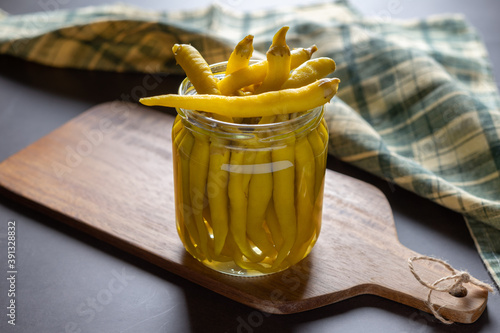 Front view of a jar of green peppers in vinegar. photo