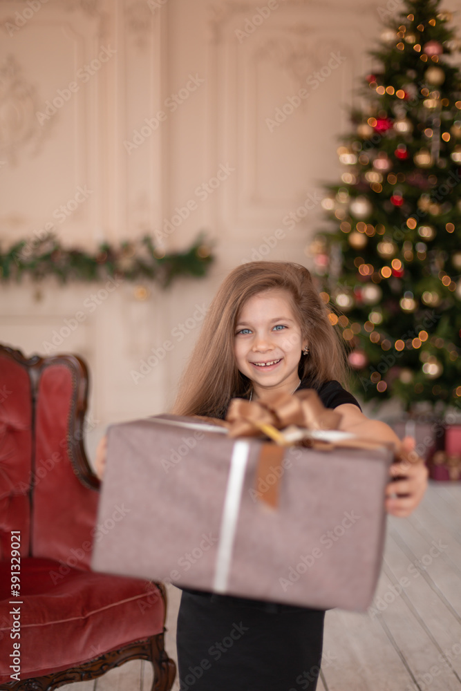 A little girl opens a Christmas present from Santa. Christmas tale. Happy childhood A little girl opens a Christmas present from Santa. Christmas tale. Happy childhood