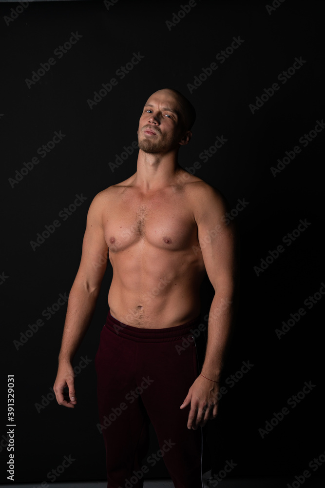 Fototapeta premium A sports guy of beautiful strength builds muscles in training. Strong bodybuilder with perfect abs, shoulders, biceps, deltoid and radial wrist flexor.