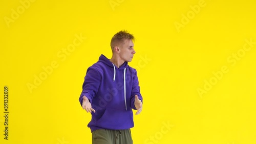 The guy  dancing hip hop, modern choreography in the studio against a yellow wall. Isolated. Medium long shot