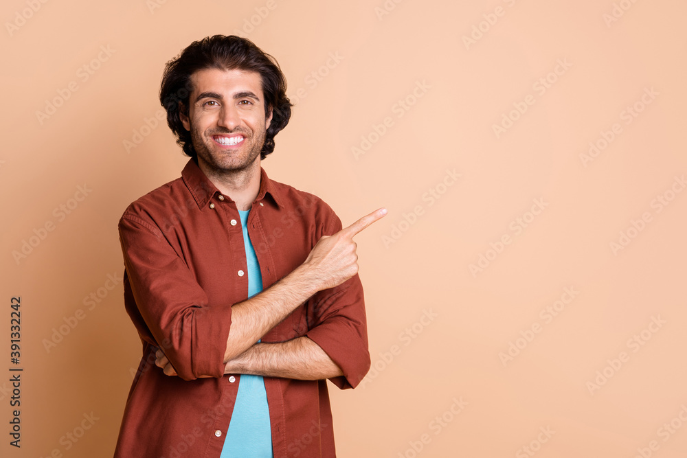 Photo of young man indicate forefinger empty space wear brown t-shirt isolated beige color background Photo of young man indicate forefinger empty space wear brown t-shirt isolated beige color background