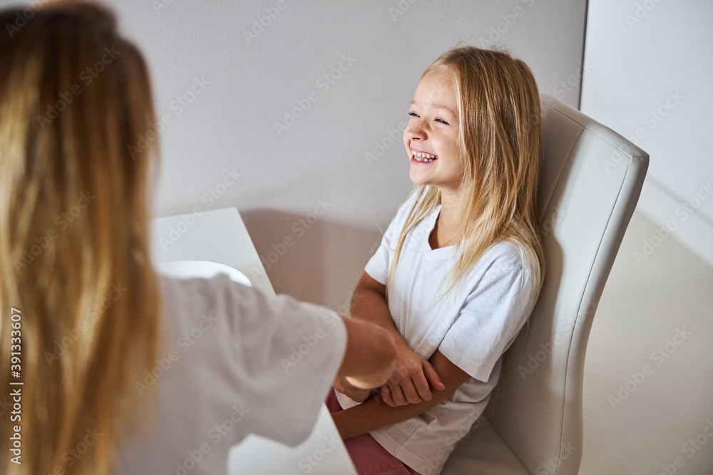Little girl laughing while talking with blonde woman in the white kitchen Little girl laughing while talking with blonde woman in the white kitchen