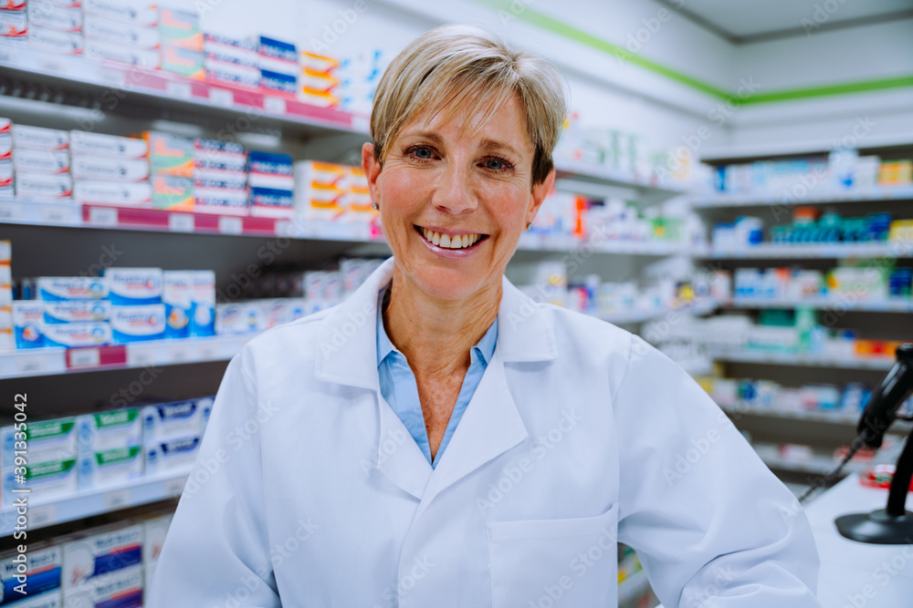 Portrait of caucasian woman pharmacist smiling in front of medication in drugstore pharmacy 