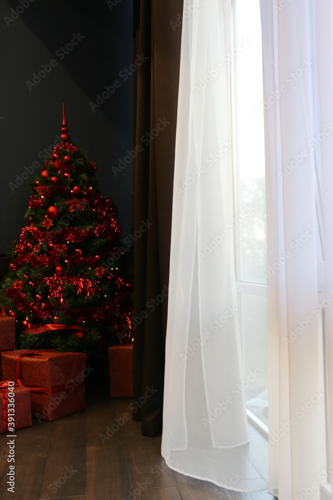 Elegant Christmas tree with red toys in the luxury apartment