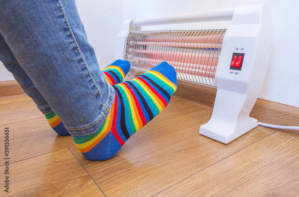 A woman wearing bright rainbowcolored socks warms her frozen feet near