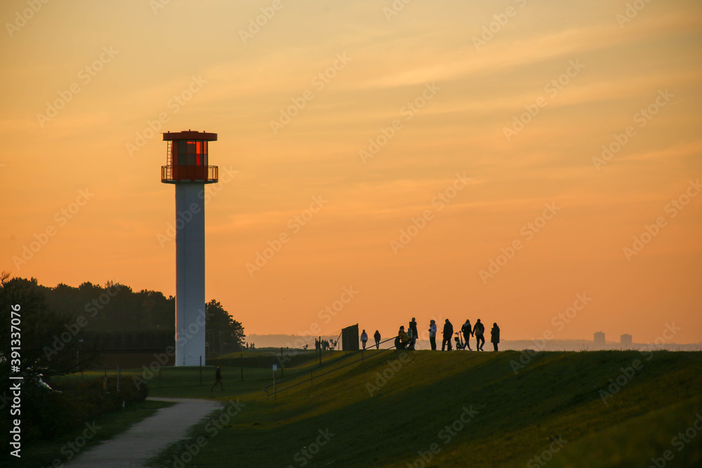 People watching the sunset with view of dyke and Baltic Sea in Heidkate, Germany