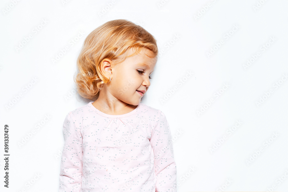 Side portrait of child girl with curly blonde hair. Studio background of white color with copy space. Side portrait of child girl with curly blonde hair. Studio background of white color with copy space.