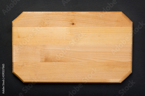 New rectangular wooden cutting board on on black stone slate plate. Mockup for food project. Top view
