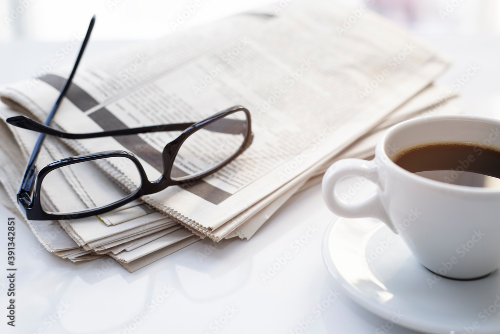 Newspapers and coffee cup, with reading glasses. Newspapers and coffee cup, with reading glasses.