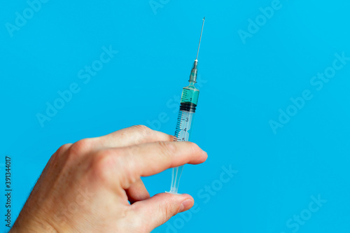 Hand holding disposable syringe on blue background