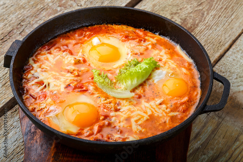 israeli fried eggs shakshuka in a frying pan on a wooden table on a stand