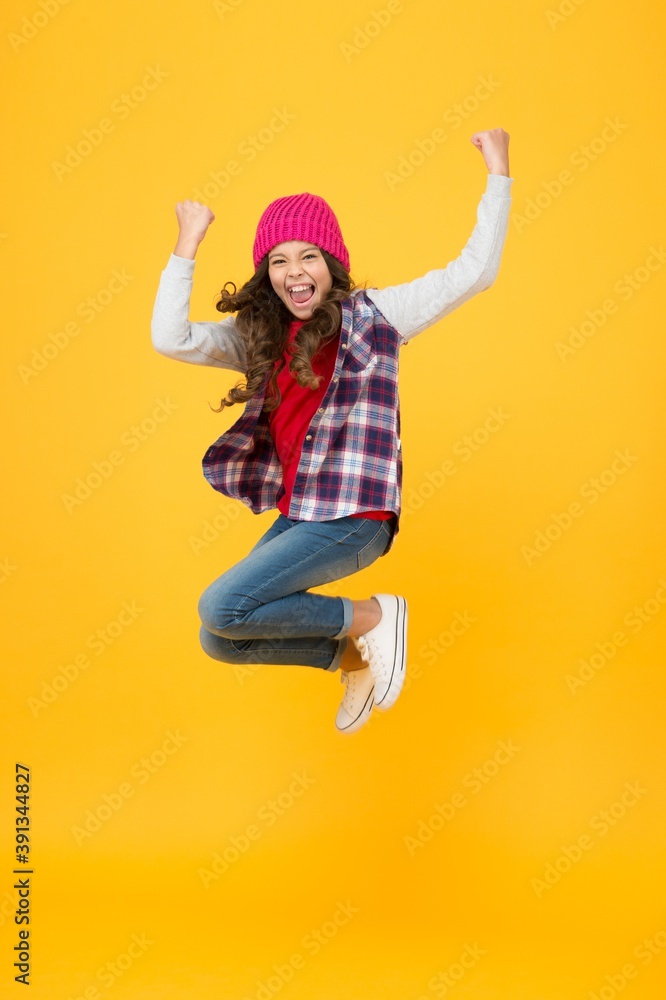 hipster look. cheerful child in knitted hat. denim fashion style. school girl on yellow background. full of energy. kid fashion and beauty. teenager jumping in casual style clothes. happy childhood