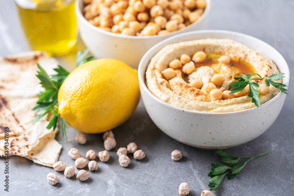 Hummus, chickpea dip, olive oil, raw beans, smoked paprika, pita on grey authentic background. Middle eastern, jewish cuisine or arabic dishes. Macro view. Copy space. Vegan, vegetarian food concept Hummus, chickpea dip, olive oil, raw beans, smoked paprika, pita on grey authentic background. Middle eastern, jewish cuisine or arabic dishes. Macro view. Copy space. Vegan, vegetarian food concept