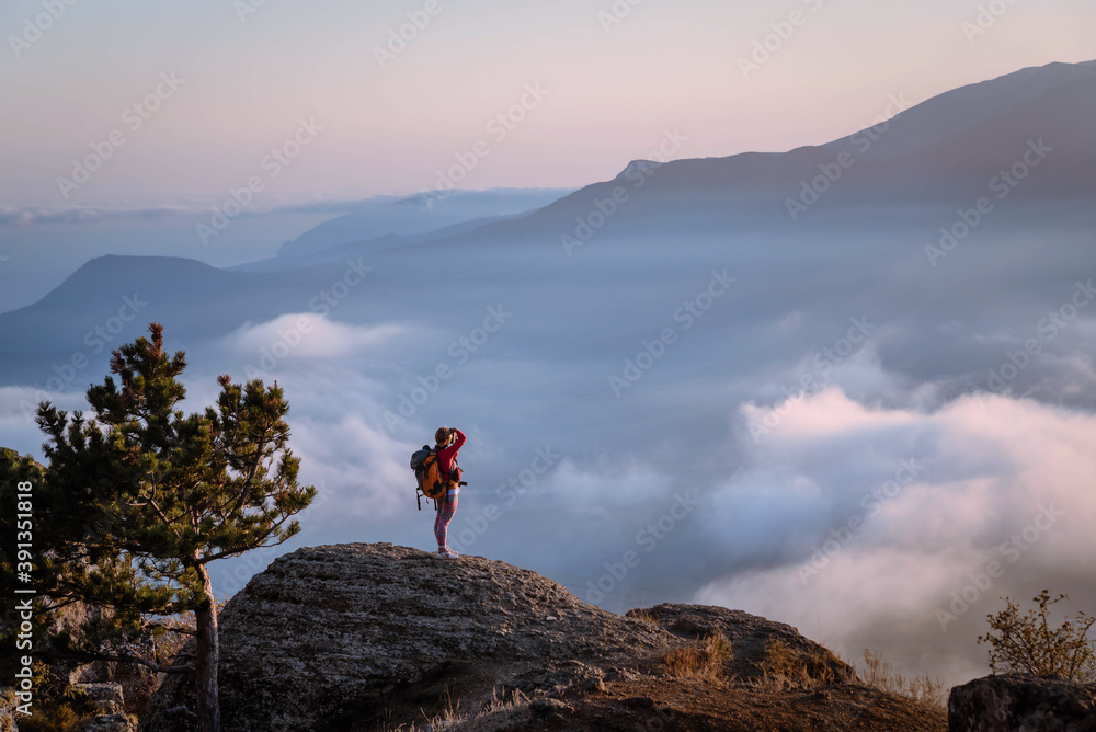 Tourist on top of a cliff above the clouds