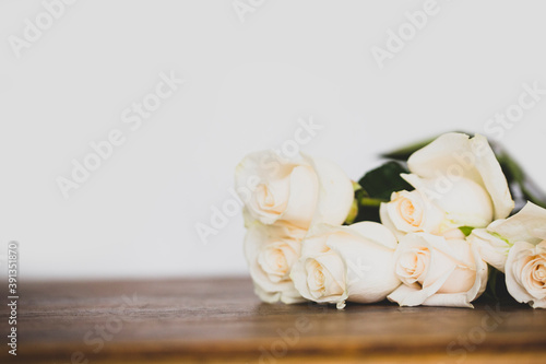 Composition with white roses on white and wooden background