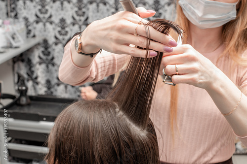 Barbershop. Hairdresser girl doing hairstyle to a young woman