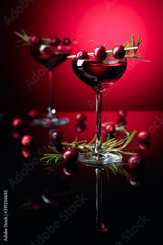 Cranberry liquor with berries and rosemary on a red background.
