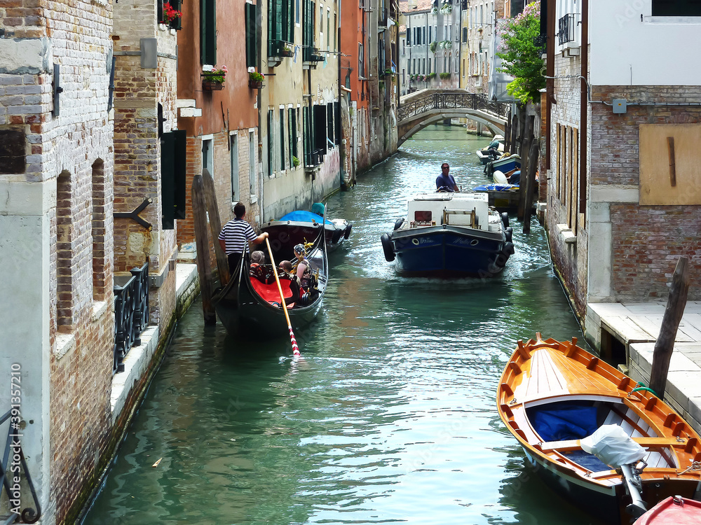 Narrow Venetian Canal. The gondola gives way to a motor boat.