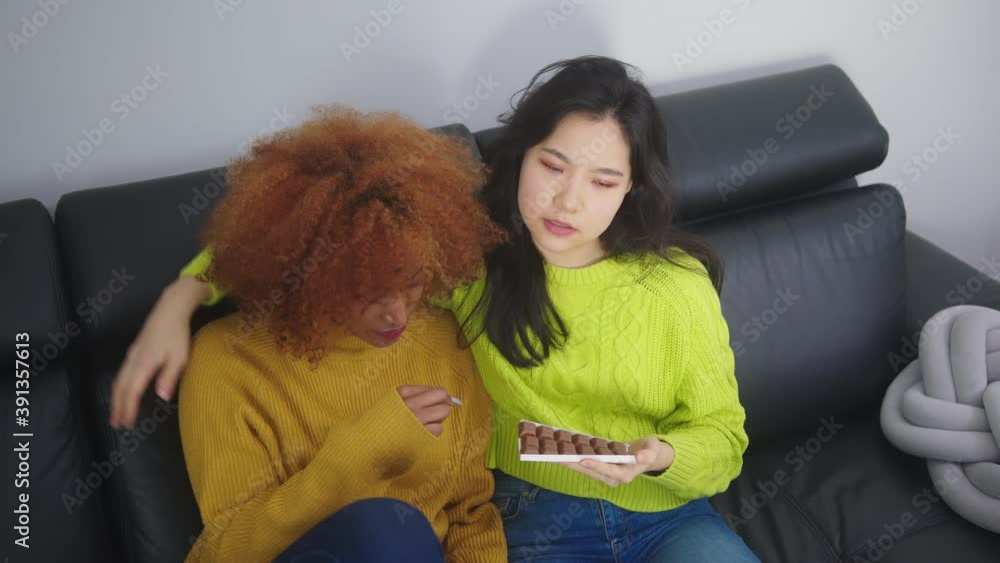 Young asian woman offering cocolate to her sad arican american black friend. Support during hard times. High quality 4k footage Young asian woman offering cocolate to her sad arican american black friend. Support during hard times. High quality 4k footage